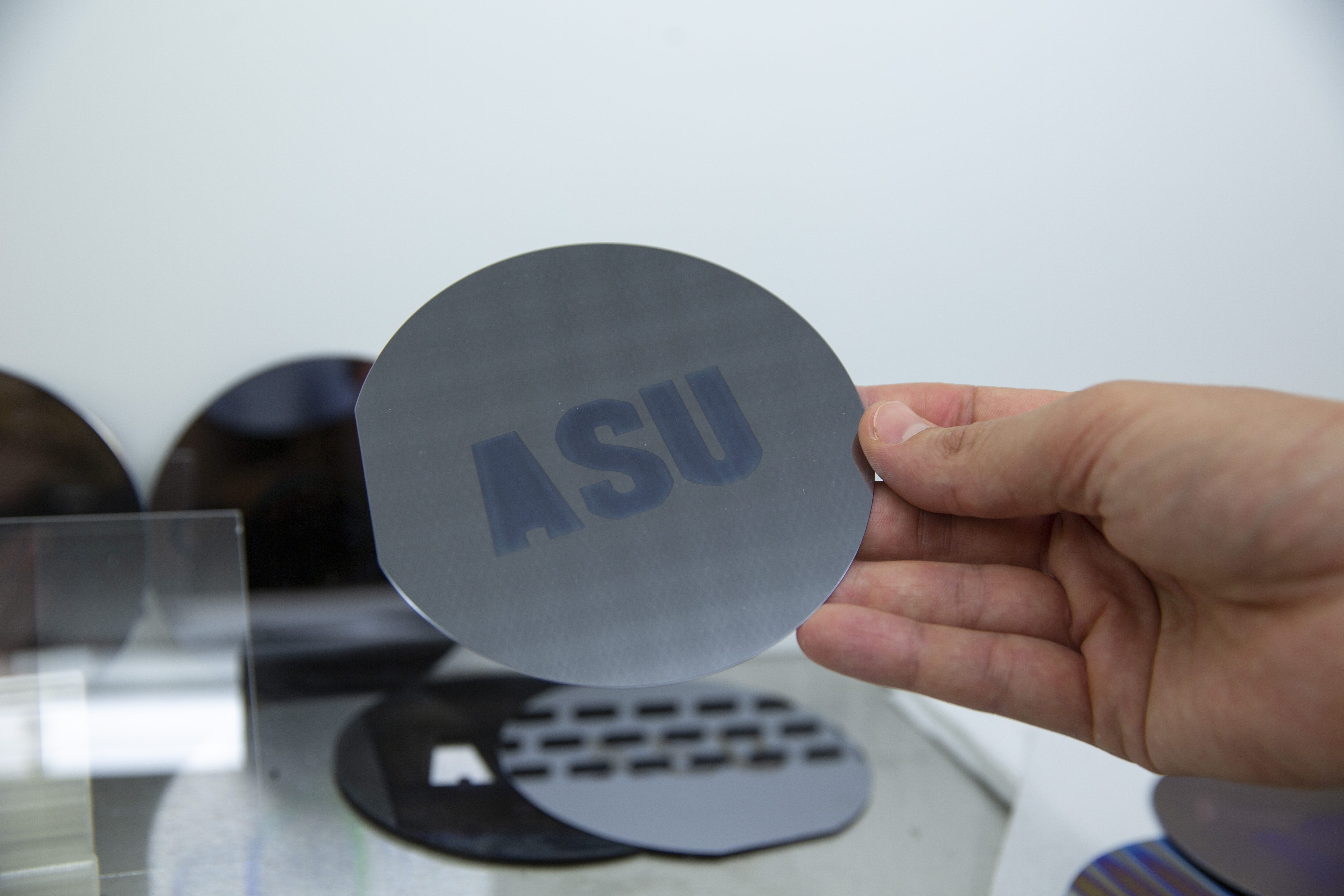 Hand holding a dark gray disc with "ASU" written on it