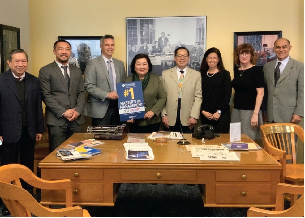 A group of people stands behind a desk holding a 