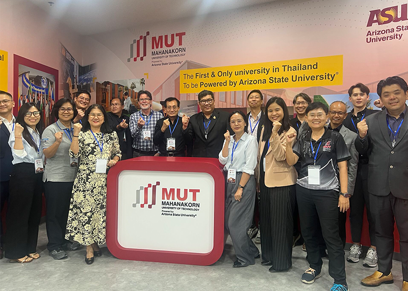 A group of people smiling and giving thumbs up behind a counter with the MUT and Arizona State University logos.